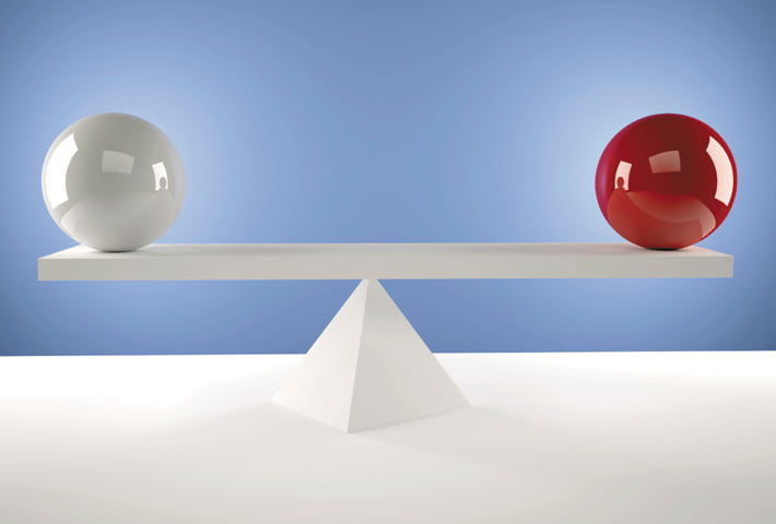 Two balls sit on either side of a balance, one of them is bright red and the other is white