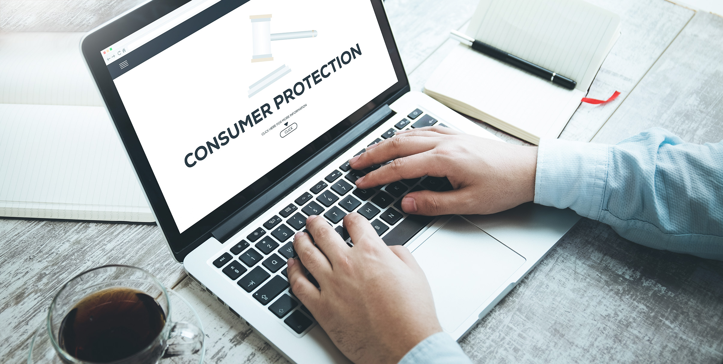 Someone's hands are resting on a laptop keyboard while the screen reads: "Consumer Protection"
