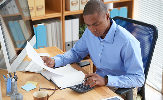 African American accountant sitting at desk looking at paperwork
