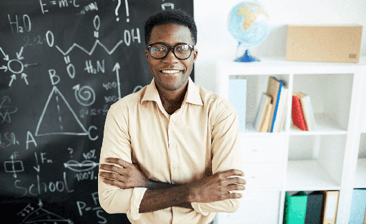 African american man with crossed arms smiling in front of a blackboard
