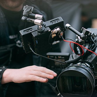 A man adjusts an advanced film camera just out of frame.