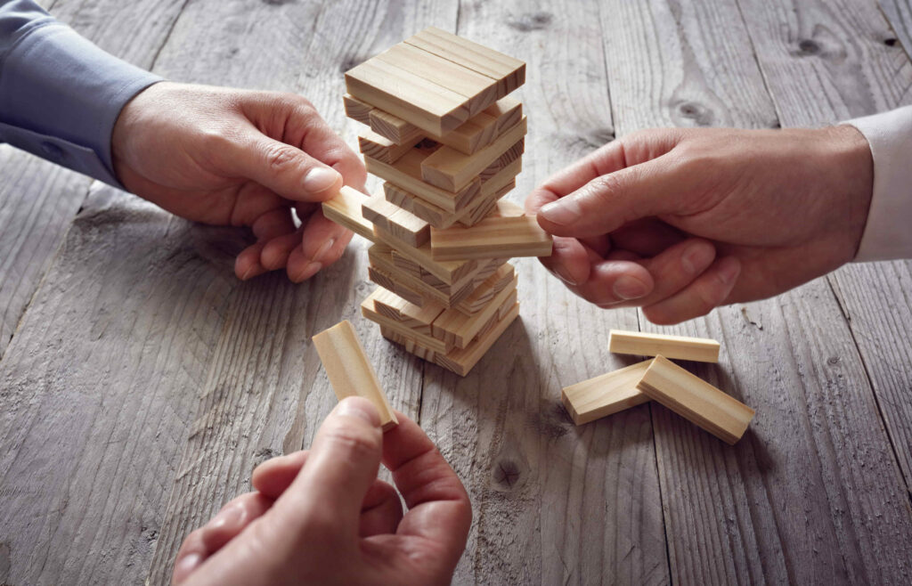 Three people pull a brick each from a Jenga tower